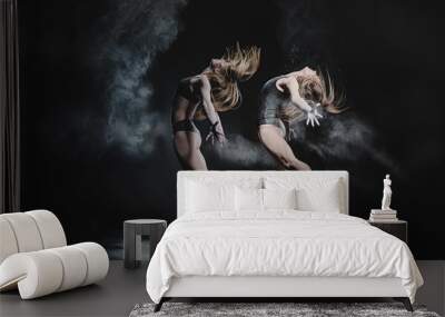 Two girls dance with flour on black background Wall mural