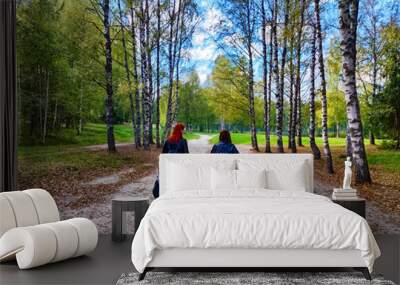 Two women walk along a path through a birch tree forest in the fall. Tourism, travel, trip, tourist, Wall mural