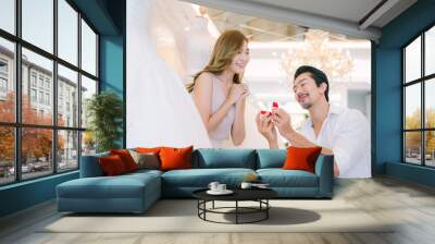 Asian man make surprise proposal of marriage to girlfriend. Attractive romantic male proposing to beautiful happy woman with wedding ring enjoying surprise engagement together. Wall mural