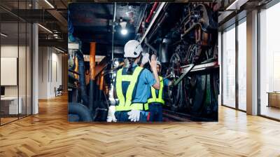 Team of engineer railway wearing safety uniform and helmet under checking under train ,wheels and control system for safety travel passenger. Maintenance cycle concept. Wall mural