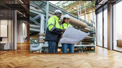 Young mechanical engineer holding blueprint drawing to checking and inspection gas pipeline system new construction project of industrial. Wall mural