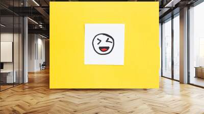 white paper with drawn laughing face on yellow background Wall mural