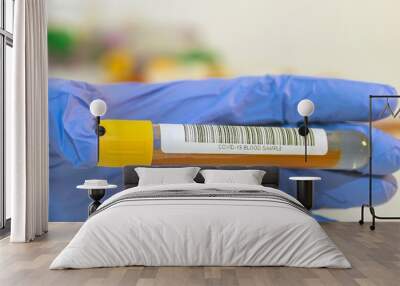 The attendant holds the blood test tube in his hand for corovirus. Wall mural