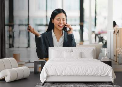 Efficient businesswoman on call, smiling while working on laptop Wall mural