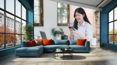 Happy young Asian woman using smartphone to interact with social media icons. Social media communication and digital online concept. Wall mural