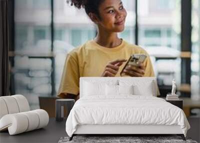 Portrait of happy young African american woman smiling confident using smartphone. afro american businesswoman reading a text message on her mobile phone. Wall mural