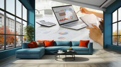 Professional analyzing financial data graphs, charts on laptop display at a modern workspace. Financial analysis or business evaluation concept Wall mural