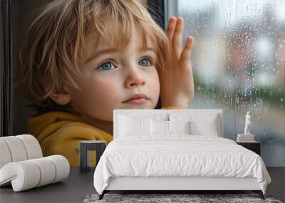 Little boy sits at the window and is sad. The boy is bored at home due to quarantine Wall mural