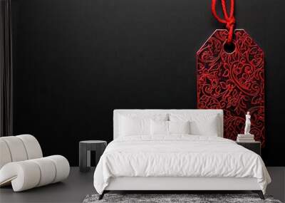 Elegant red tag with ornate patterns suspended against a deep black backdrop, offering ample space beneath for promotional messaging and captivating advertising content. Wall mural