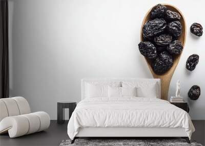 Dried prunes on wooden spoon against white background Wall mural