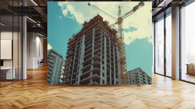 Urban construction site with tower crane and high-rise building under clear sky Wall mural