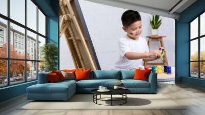 Cute happy little Asian boy painting with watercolor on canvas standing in white room at home, creative young artist at work. Kids paint. Children draw. Wall mural