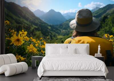 woman with yellow backpack and hat enjoys vibrant mountain landscape filled with yellow flowers under clear blue sky, evoking sense of adventure and tranquility Wall mural