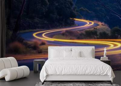 Cars light up trails on a curved paved road. Wall mural