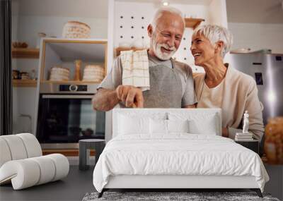 An older couple cooking a healthy vegan meal with vegetables together Wall mural