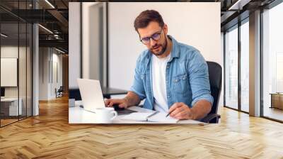 Business man working in office with laptop and documents on his desk. Wall mural