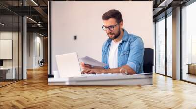 Business man working in office with laptop and documents on his desk. Wall mural