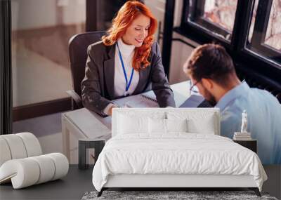 Business people man and woman sitting at the table in the office and signing the contract. Wall mural