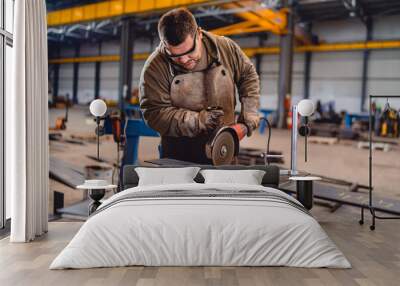 Factory worker cutting metal with grinder. Wall mural