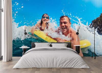 Father and daughter having fun on the beach while floating on airbed Wall mural