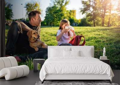 Girl blowing nose and sitting on grass with father Wall mural