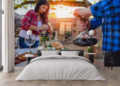 Men holding wine decanter above dining table Wall mural