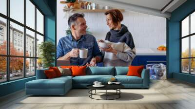 Men using laptop and driking coffee at home and talking with his wife Wall mural