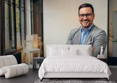 Portrait of young businessman standing in his office with arms crossed Wall mural