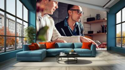 Two designers sitting at meeting table and using laptop Wall mural