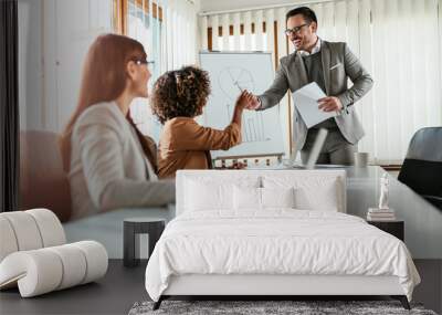 Woman giving his colleague white board marker at the meeting Wall mural