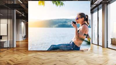 Woman relaxing by the sea and drinking coffee Wall mural