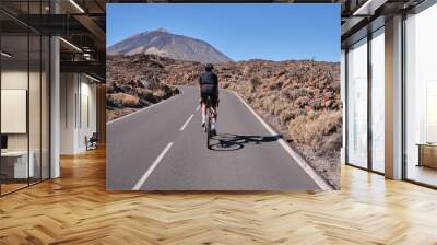 Male cyclist pedaling on road with view on mountain Teide volcano,Tenerife,Canary Islands,Spain. Sportsman training hard on bicycle outdoors.Sport motivation.Cycling training outdoors.Hipster cyclist. Wall mural