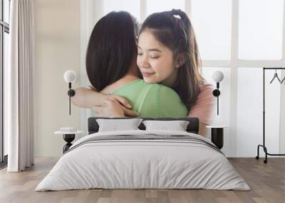 Teenage asian girl hugging her mother in living room with window light, love and care mom concepts. Wall mural