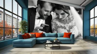 a bride and groom looking at a cell phone Wall mural