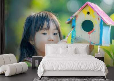 a little girl holding a bird house in her hand Wall mural