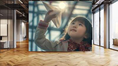 a little girl holding a paper airplane in her hand Wall mural