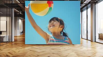 a little girl playing with a beach ball Wall mural