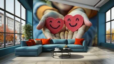 a person holding two hearts with faces drawn on them Wall mural