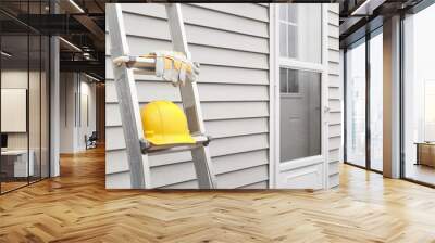 Yellow hard hat and work gloves on ladder with house siding background. Wall mural