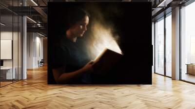 Reading a glowing book Wall mural