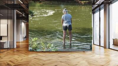 A lady crabbing using a line on the shallow water near Assateague Island, Maryland, U.S.A Wall mural