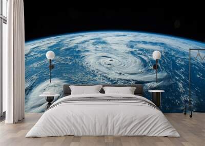 A view of Earth showcasing two hurricanes swirling over the ocean from space. Wall mural