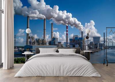 Coal power plant with towering smokestacks emitting plumes of smoke against a backdrop of blue skies and fluffy white clouds Wall mural