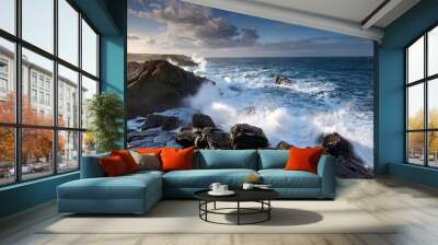 Sunset over the coast with waves crashing on rocky shores Wall mural