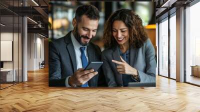 Two business professionals, a man and a woman, are reviewing information on a smartphone Wall mural