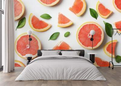 Vibrant, juicy grapefruit slices and wedges with a few green leaves scattered Wall mural