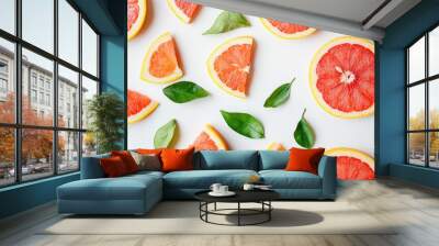 Vibrant, juicy grapefruit slices and wedges with a few green leaves scattered Wall mural