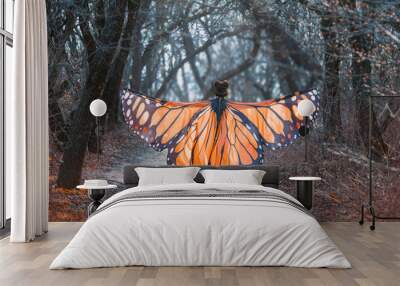 A bright, positive, sunny monarch butterfly, with huge wings, walks in a dark gray forest. Art photo from the back without face. Mysterious fairy takes off into the air. Creative colors Wall mural