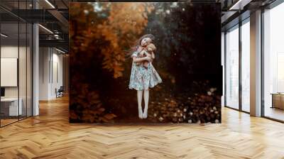 dream of cute girl with flying hair hovers above ground with teddy bear in hands. child in long light dress with floral pattern levitates in dreams and hugs toy, creative magical photo in air Wall mural