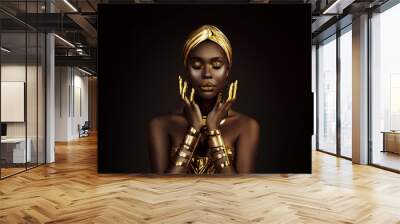 Portrait closeup Beauty fantasy african woman face in gold paint. Golden shiny black skin. Fashion model girl goddess hand fingers posing. Arab turban jewellery bracelets. Professional metallic makeup Wall mural